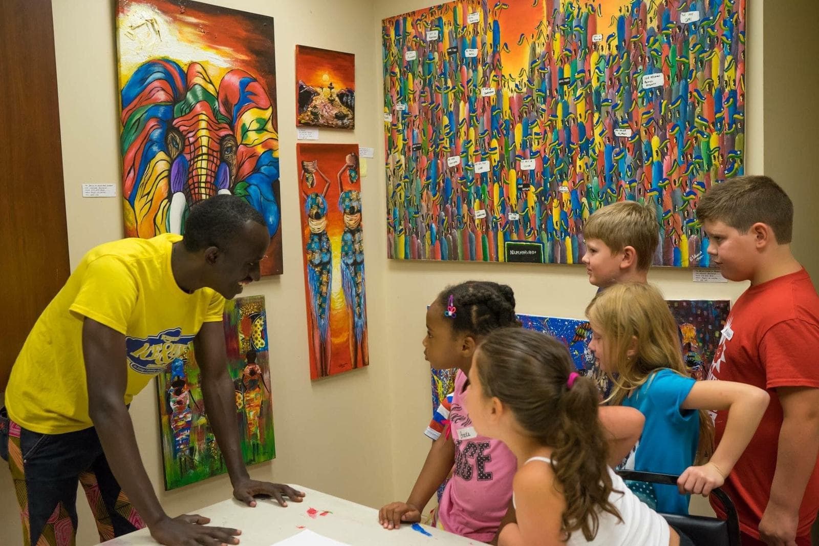 Bertrand Ishimwe showing his paintings to children in the United States