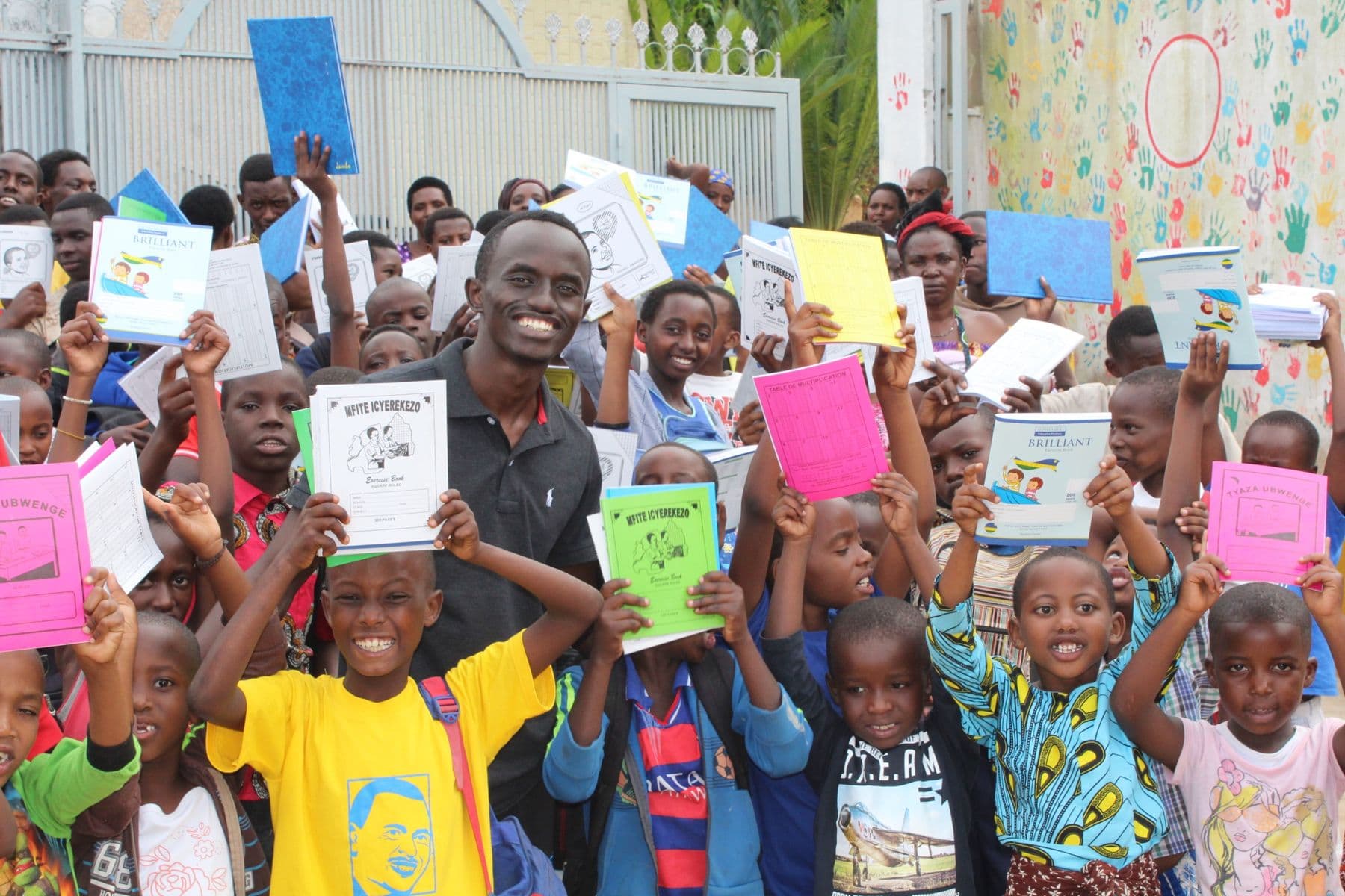 Bertrand Ishimwe with children holding up their new exercise books