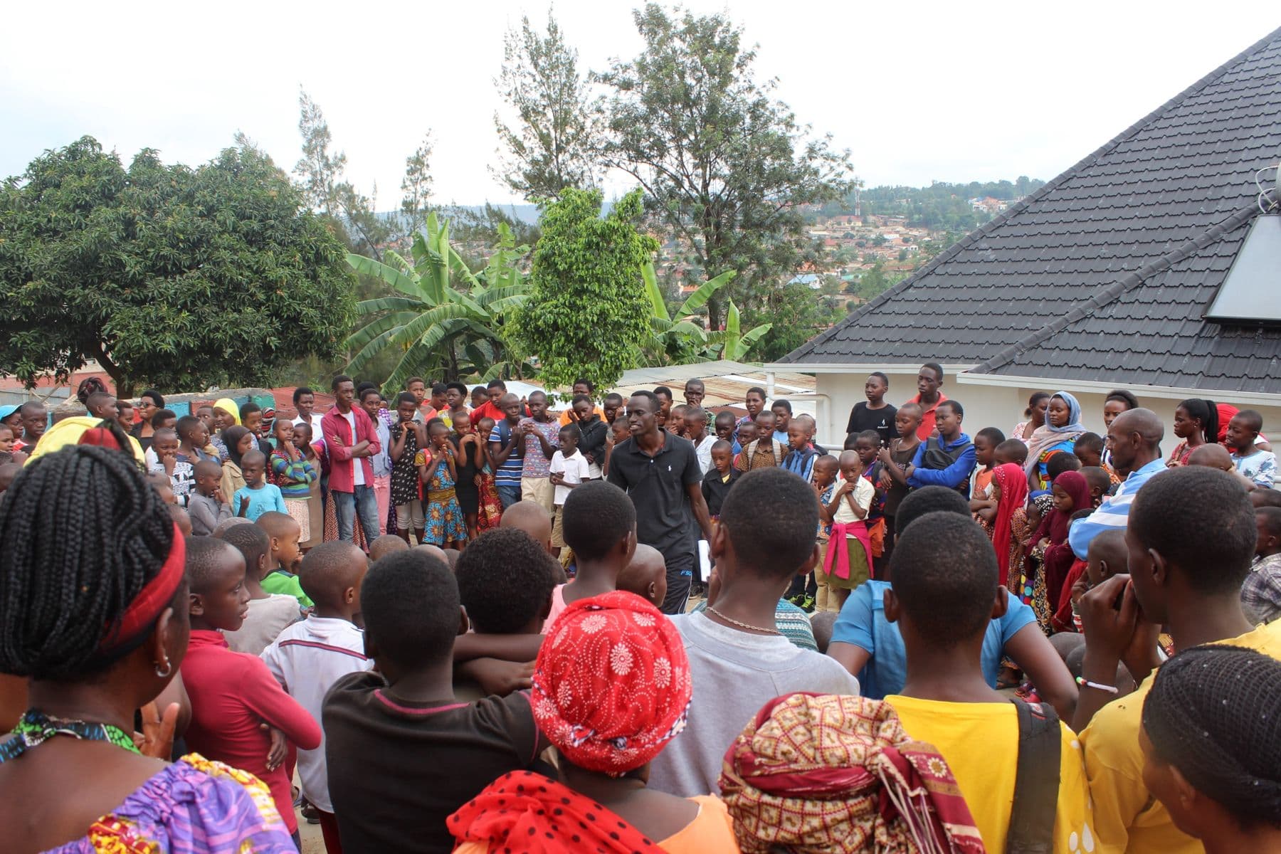 Bertrand Ishimwe speaking to children and families gathered at the community center