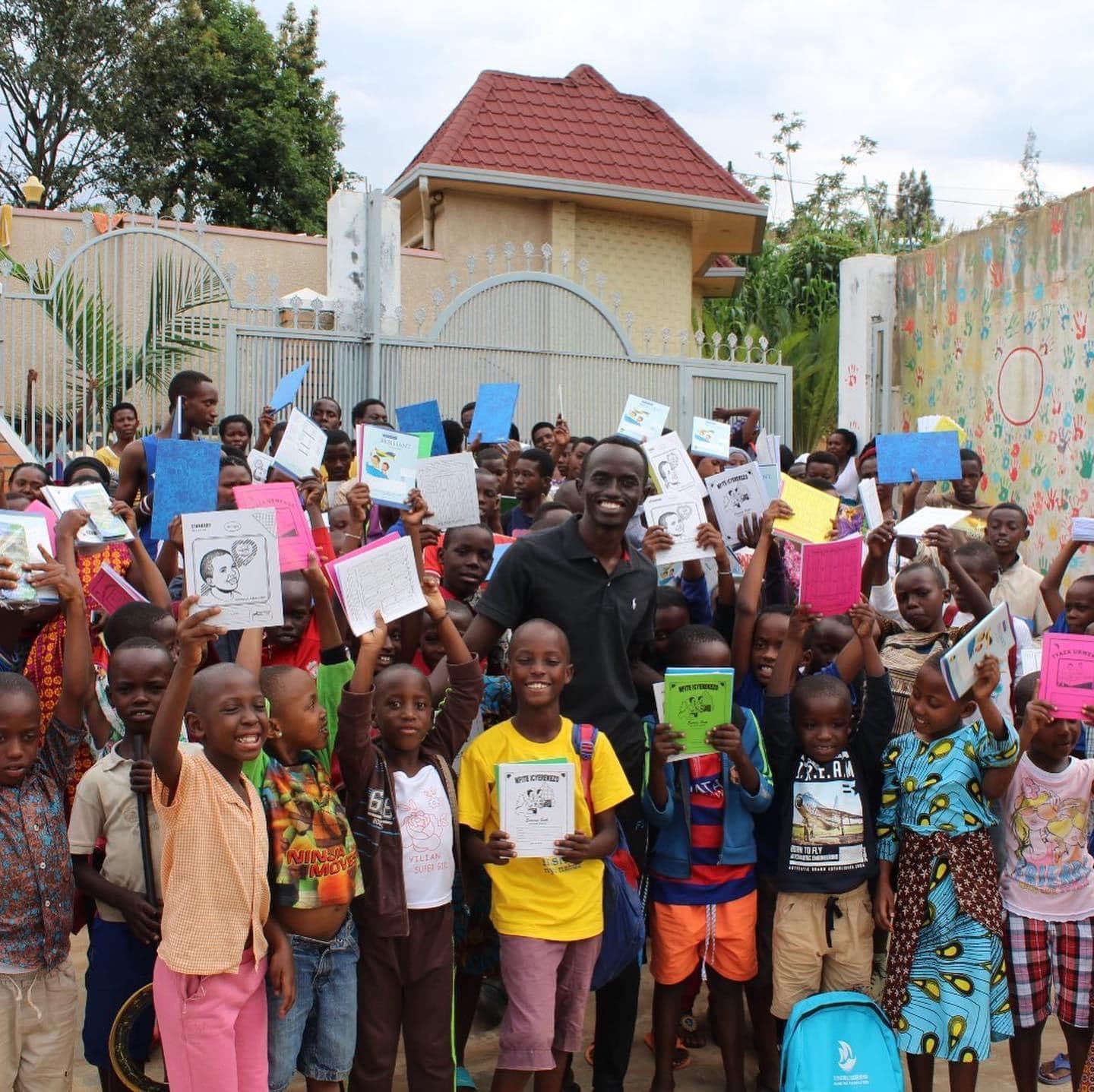 Bertrand Ishimwe with children holding new school supplies