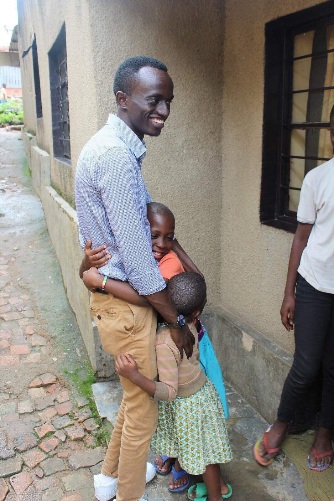 Bertrand Ishimwe being hugged by two children in Kigali