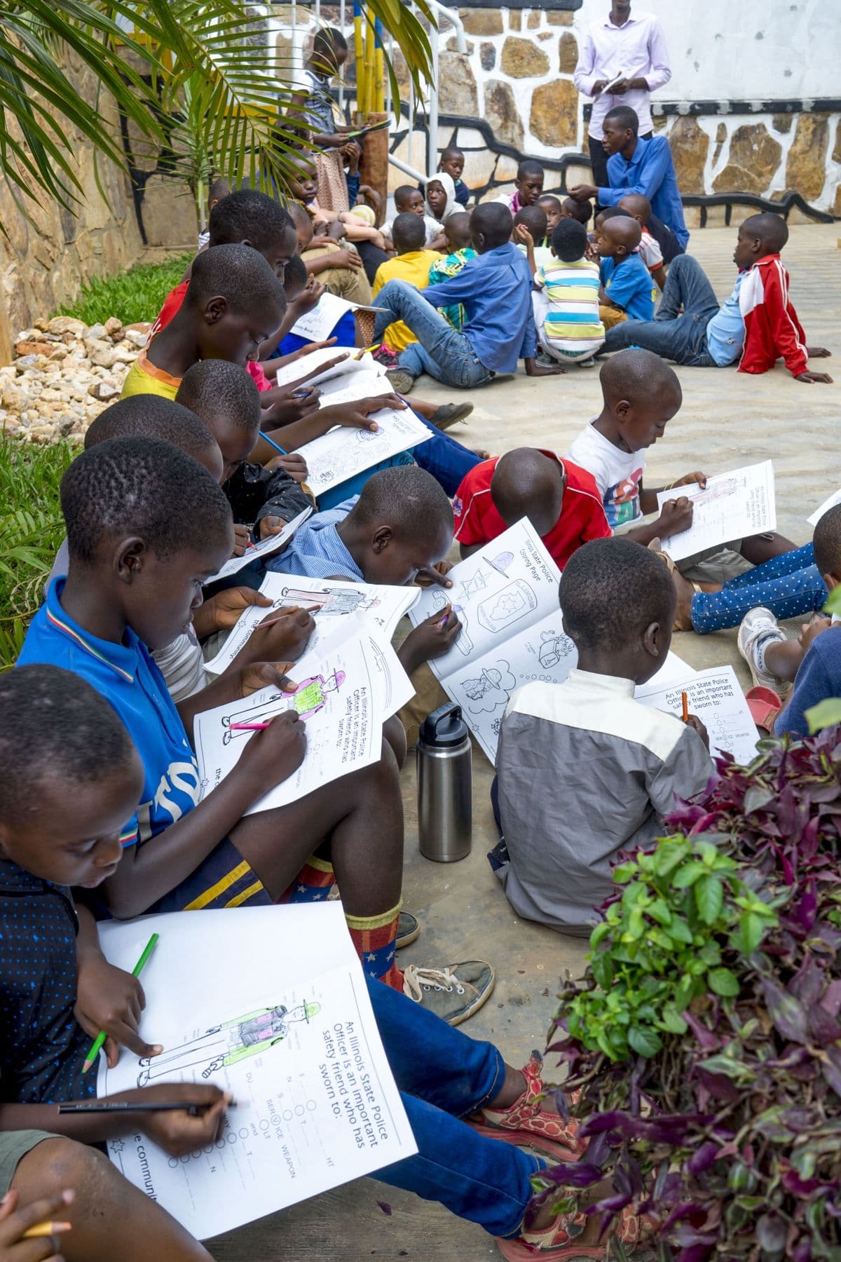 Children sitting in a row, coloring their activity sheets