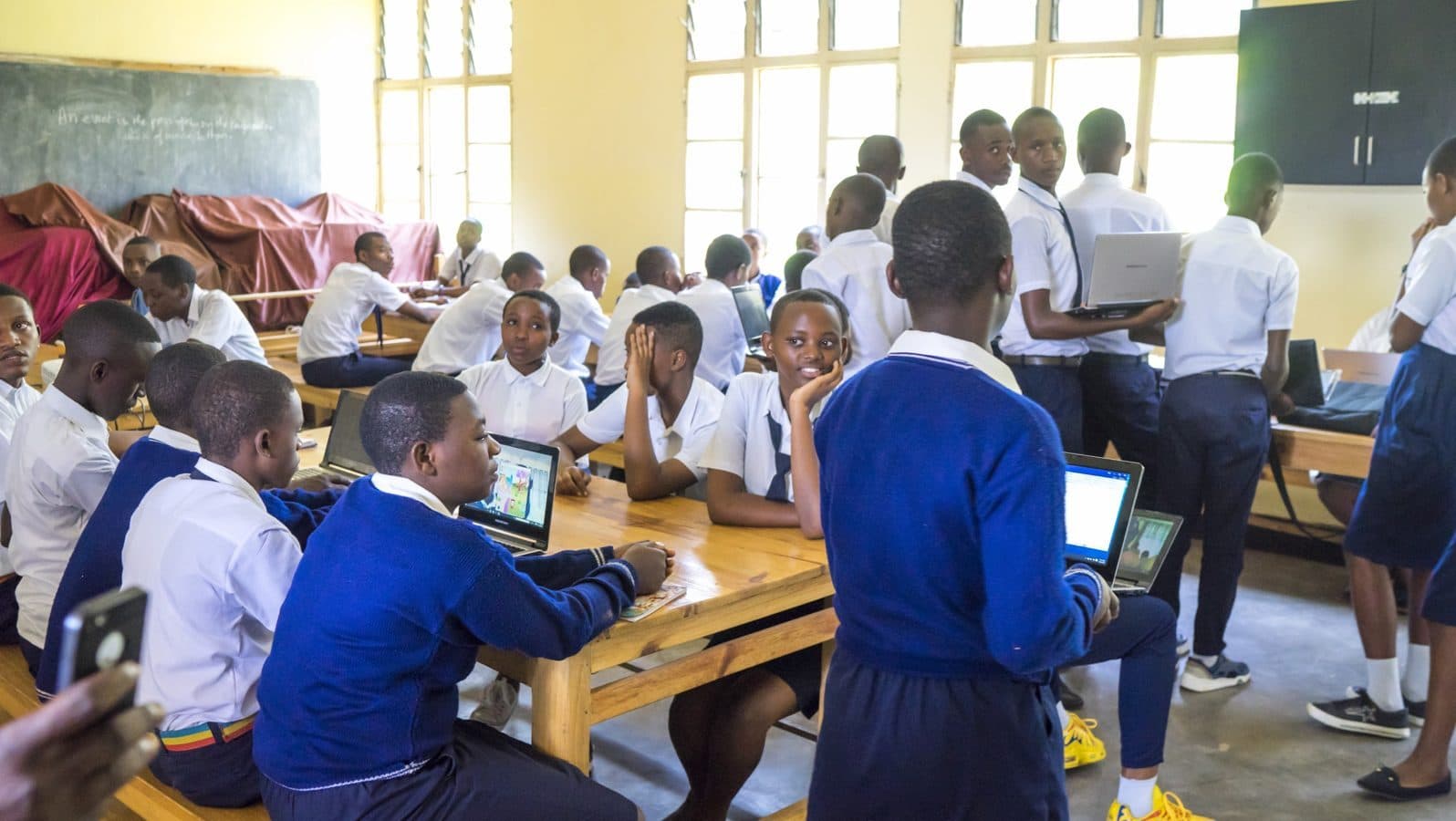 Students in school uniform learning on laptops during a computer lesson