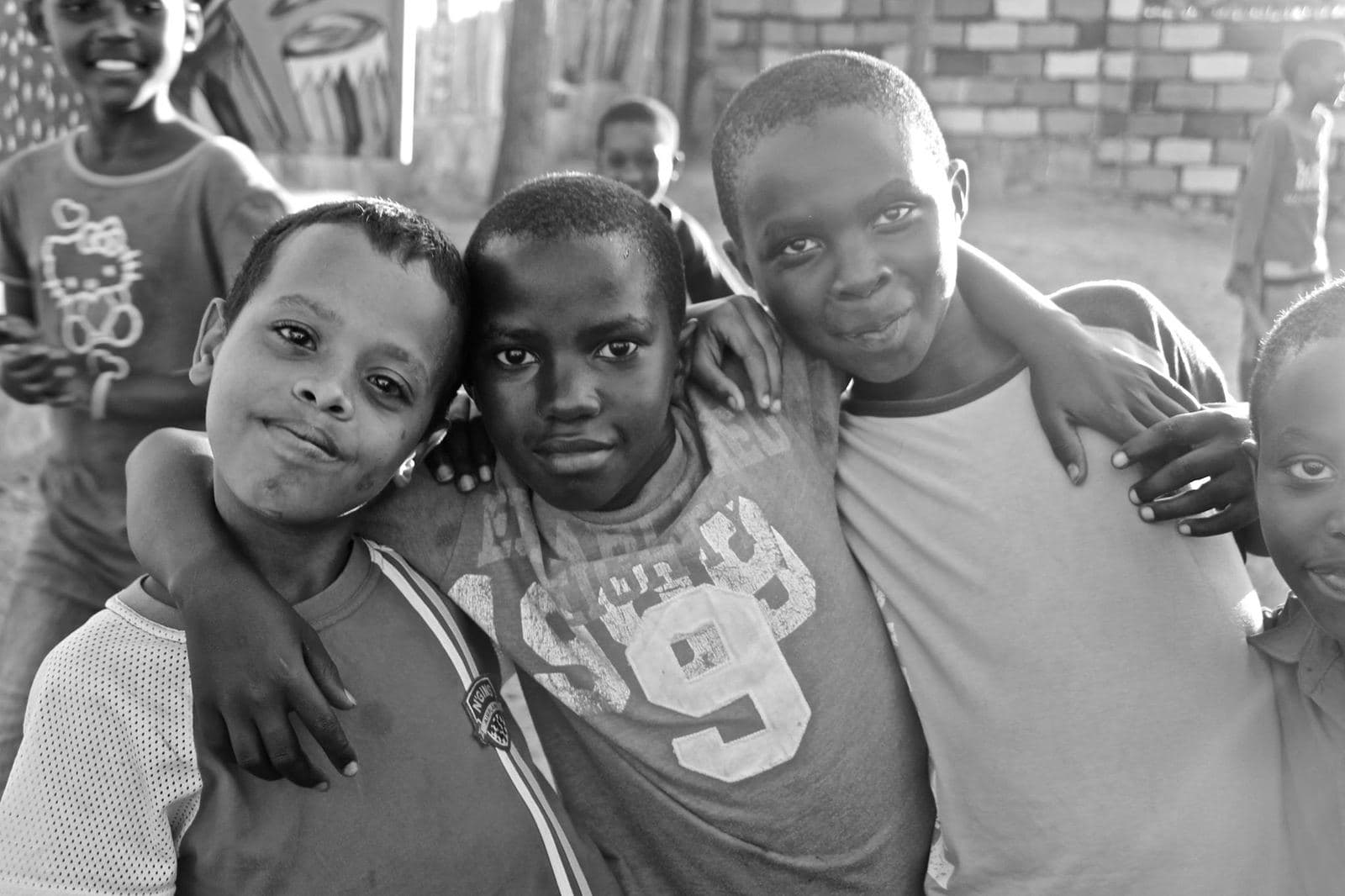 Three boys with their arms around each other, smiling