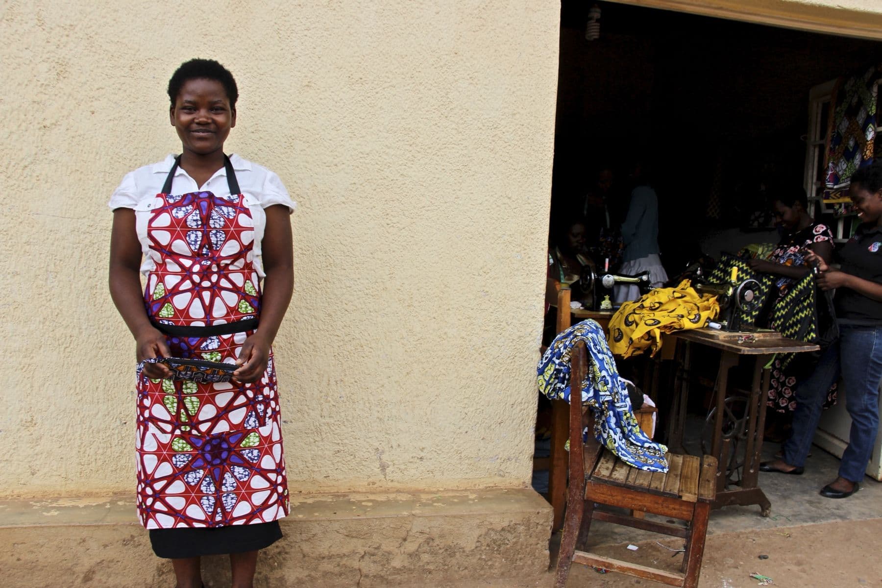 A Mama Rwanda trainee in an apron she made, outside the sewing workshop