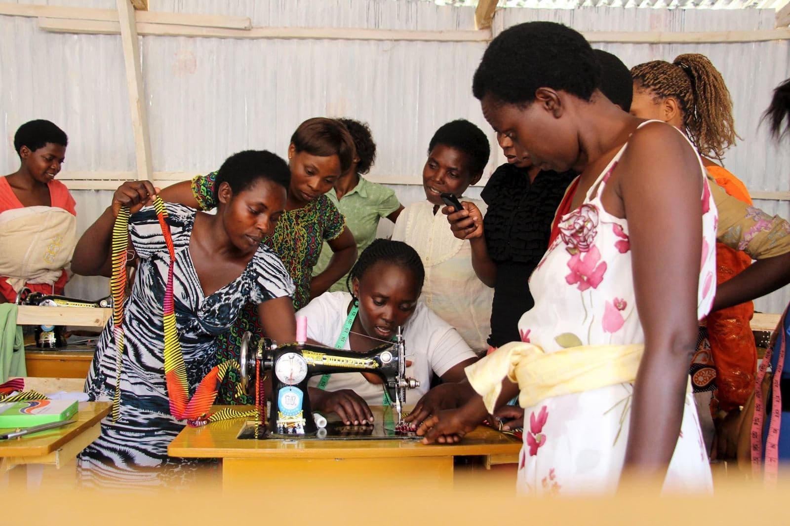 A trainer showing women how to use a sewing machine