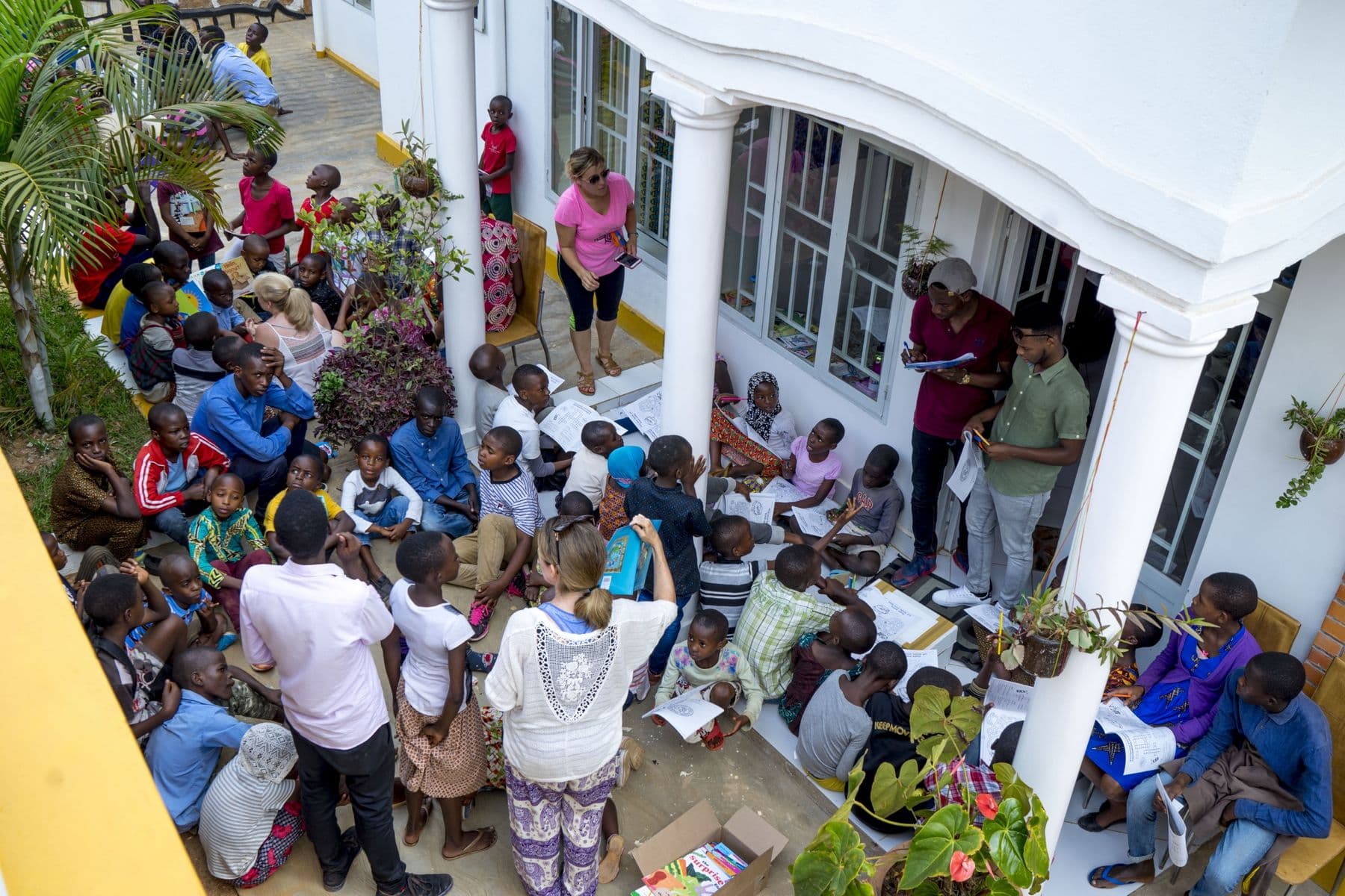 Children reading and coloring with volunteers in the courtyard