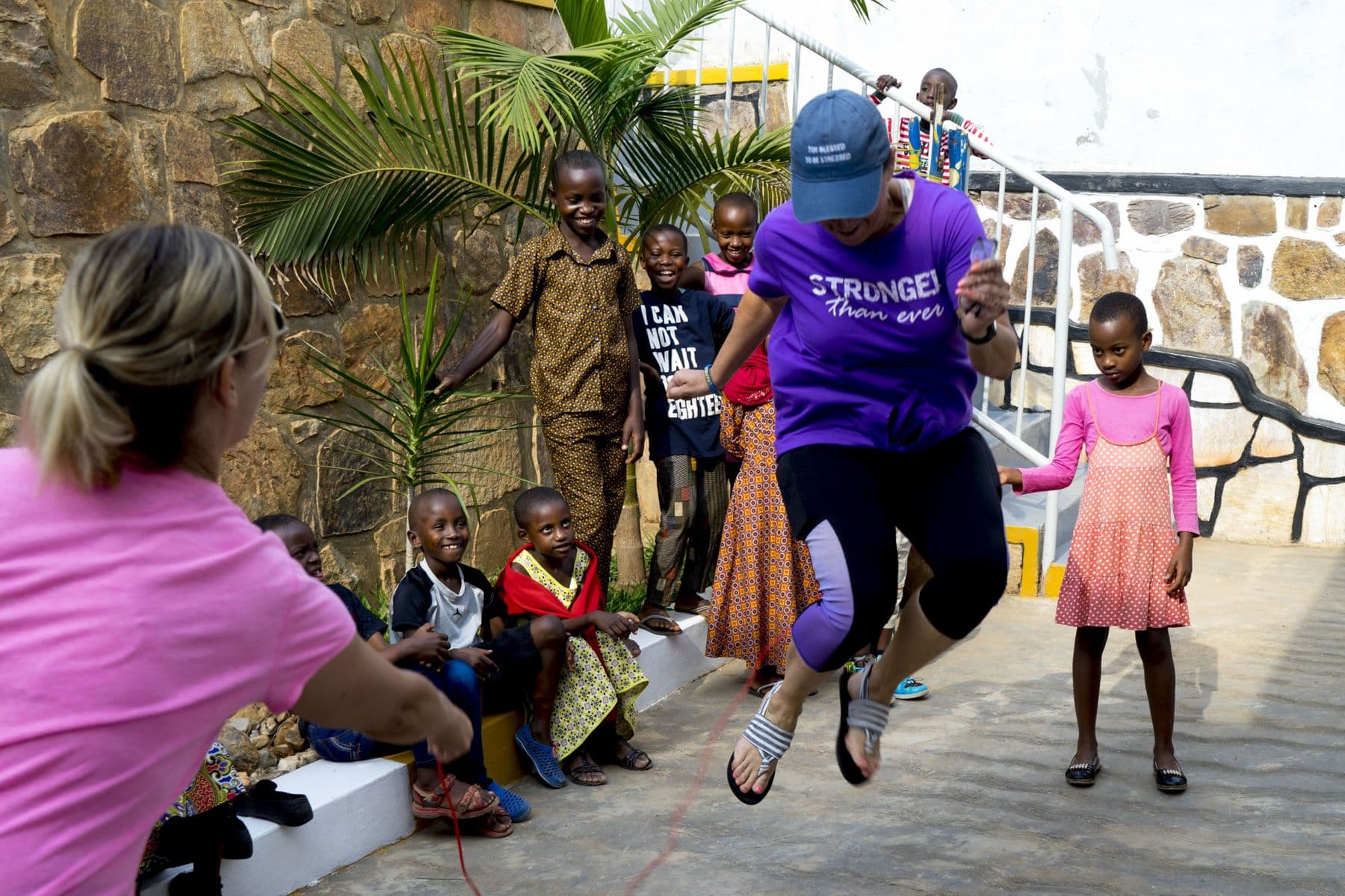 A visitor jumping rope while children laugh and cheer