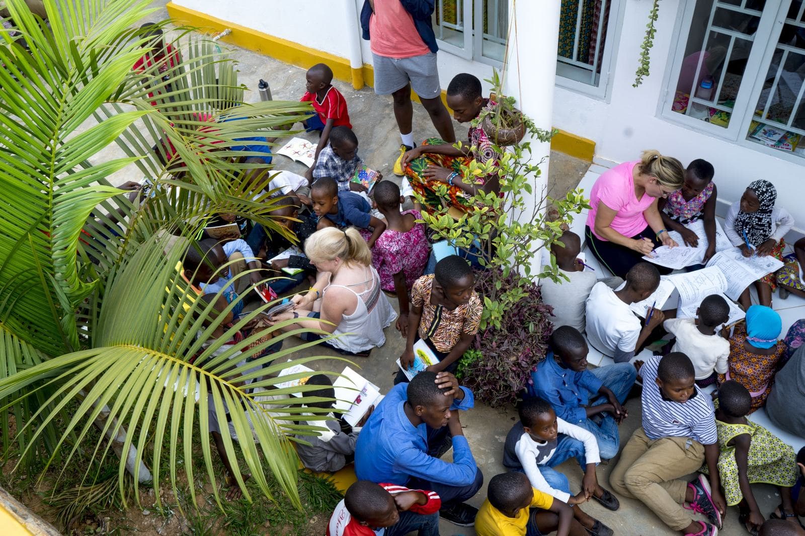 Children reading and coloring with volunteers in the courtyard