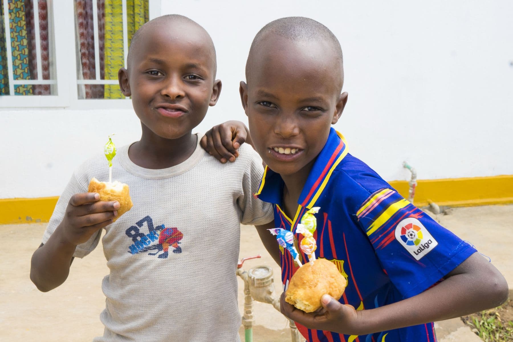 Two boys smiling with their bread rolls and lollipops