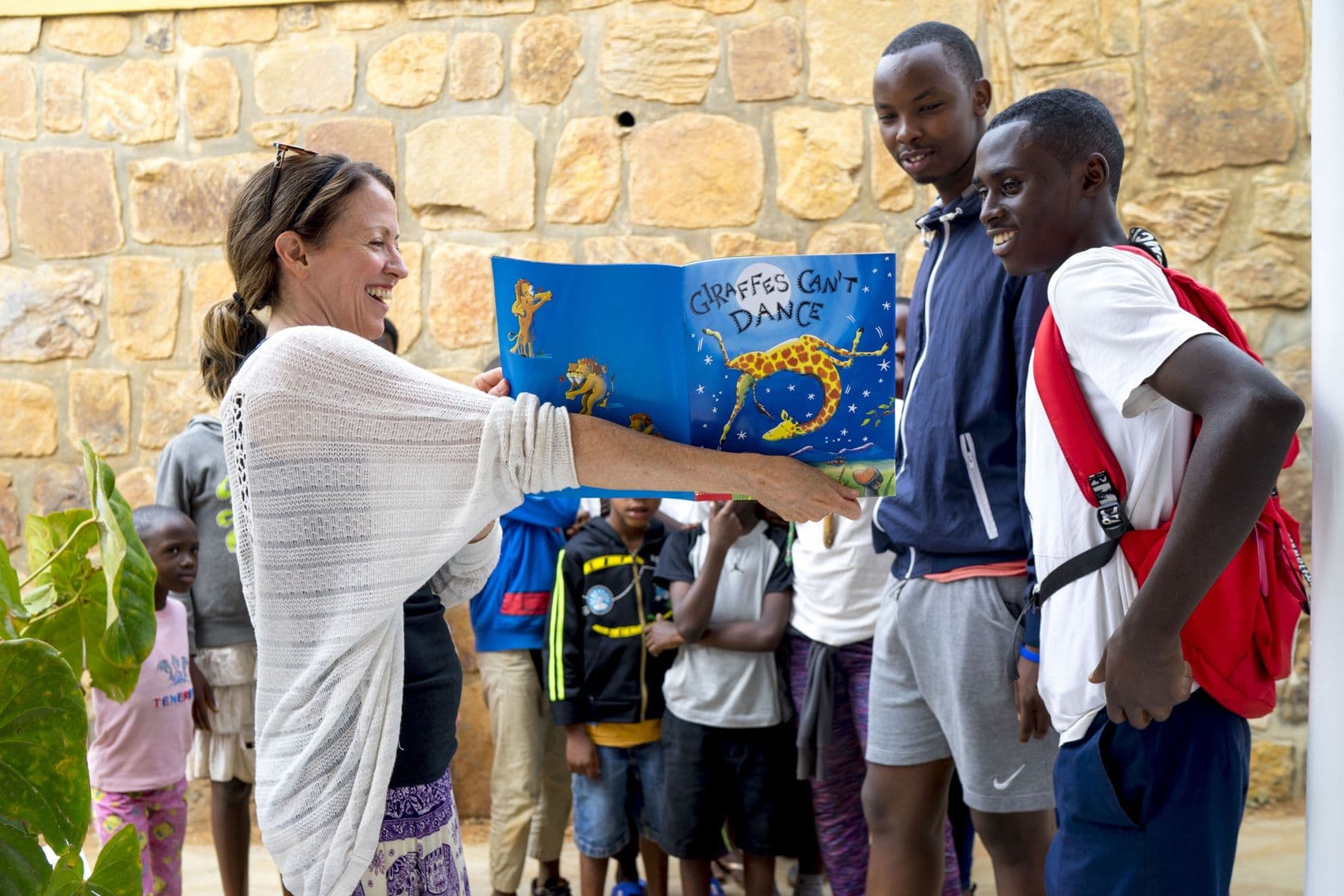 A visitor reading a picture book with Irembo youth