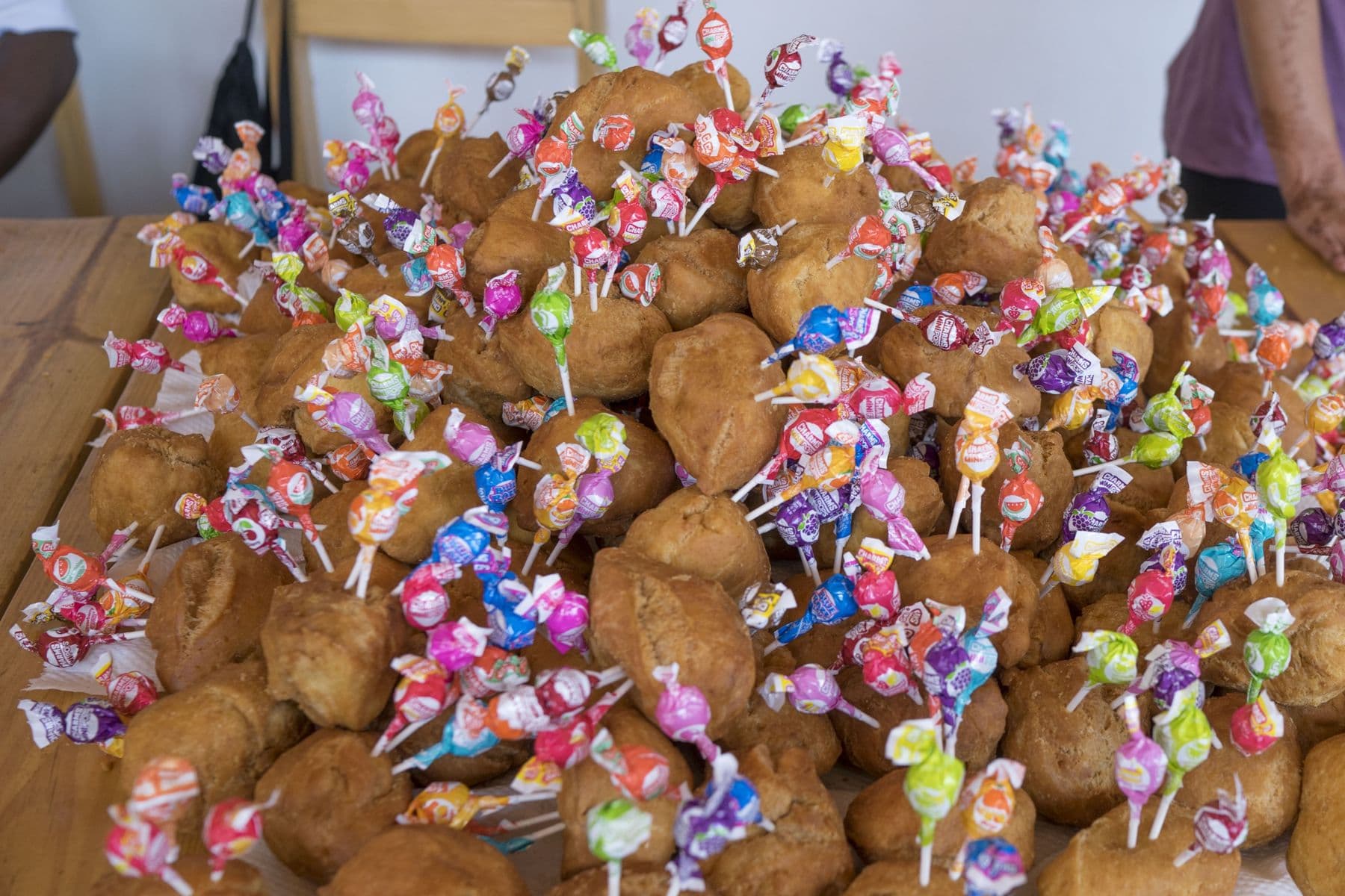 A table piled with bread rolls, each topped with a lollipop