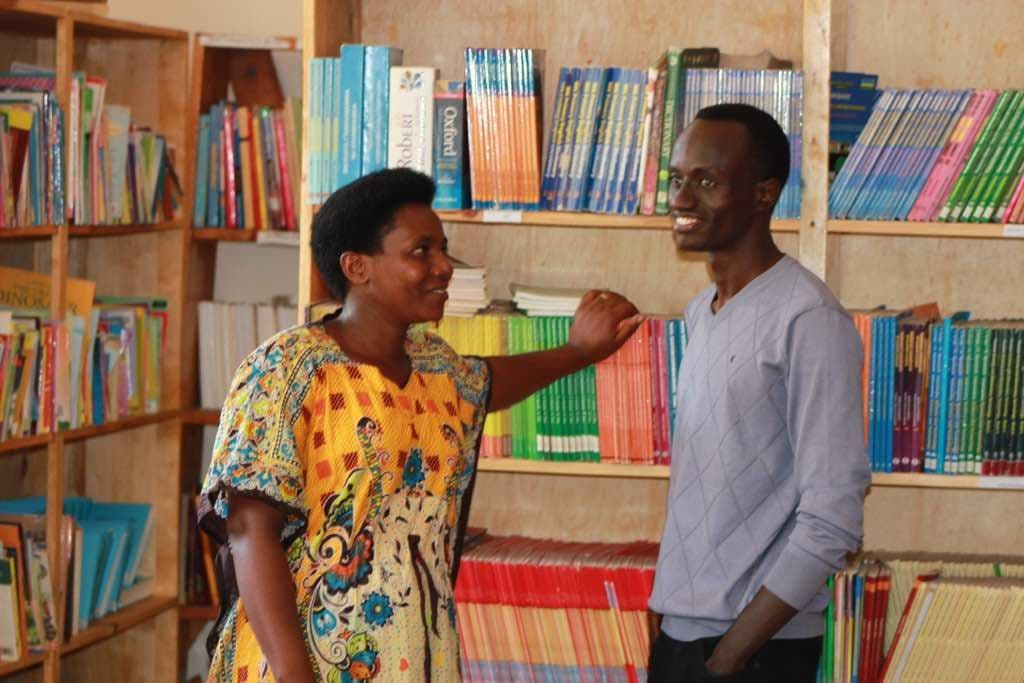 A parent and an Irembo team member talking in a school library
