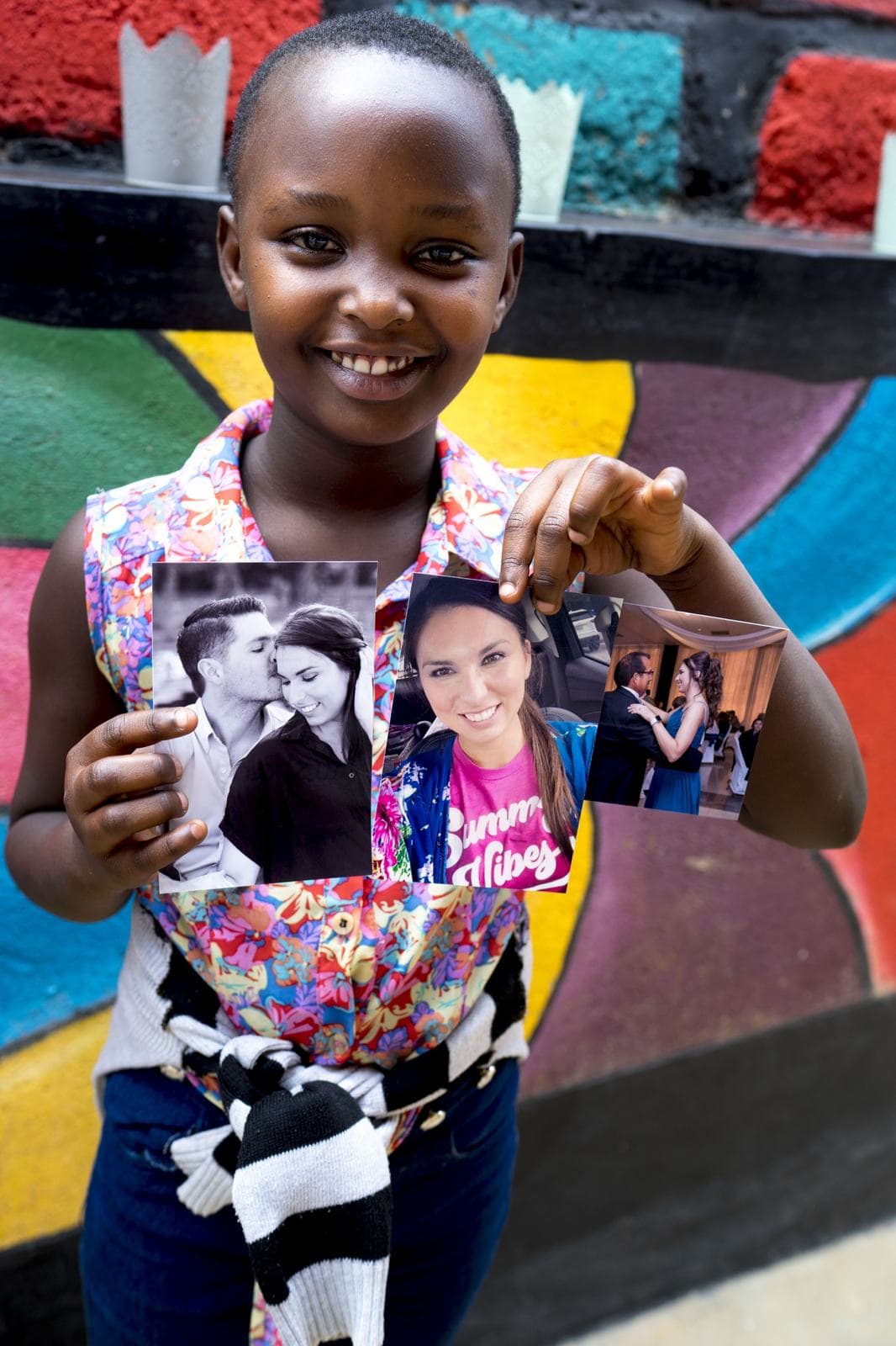 A girl holding photos from her sponsor family
