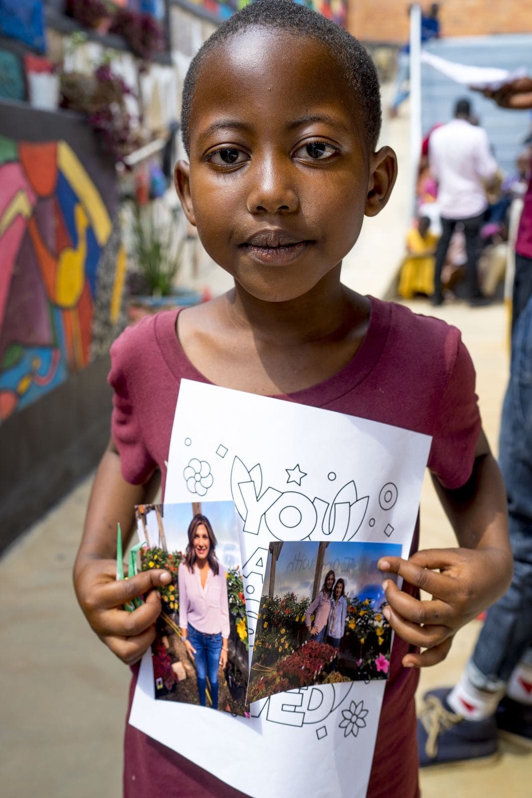 A child holding photos and a card from her sponsor