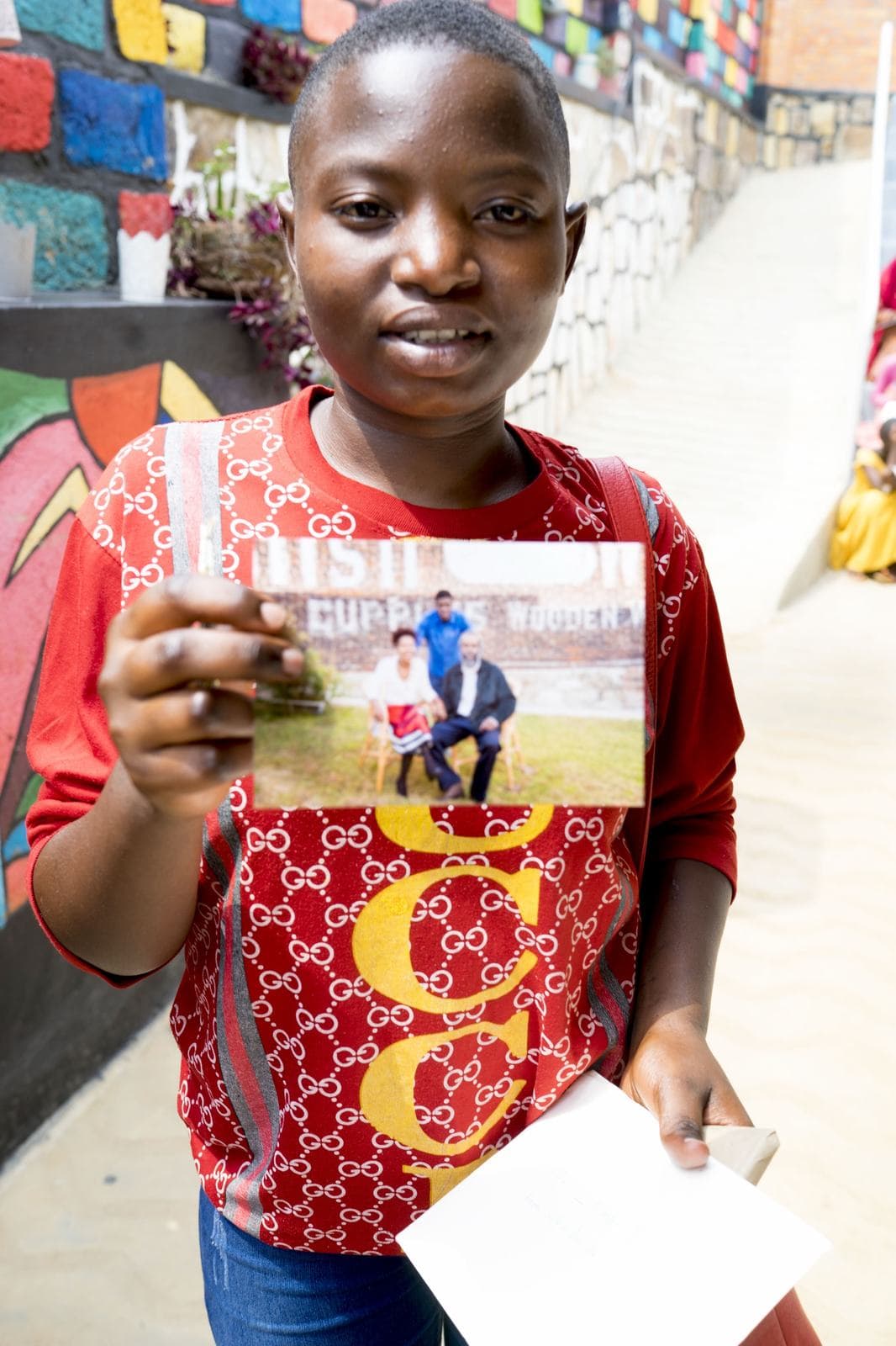 A young person holding a photo sent by their sponsors