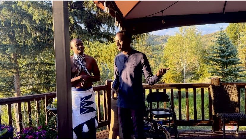 Bertrand Ishimwe speaking beside a traditional Rwandan dancer at an Irembo US gathering