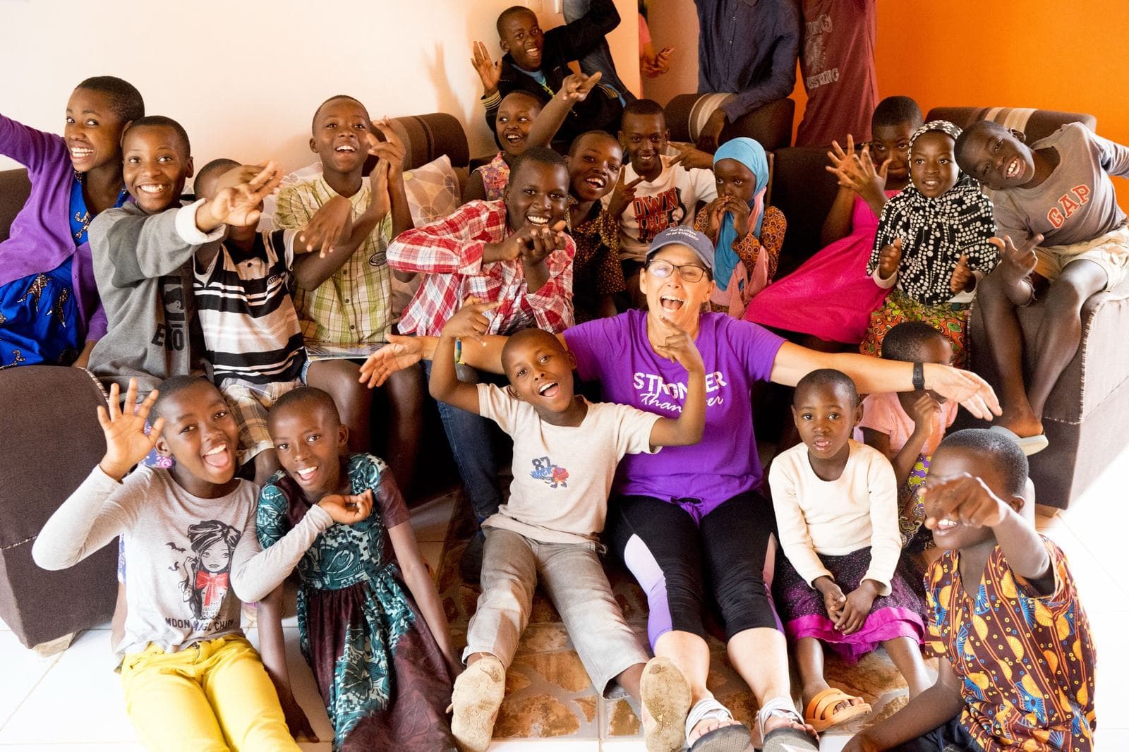 A visitor laughing with a group of Irembo children