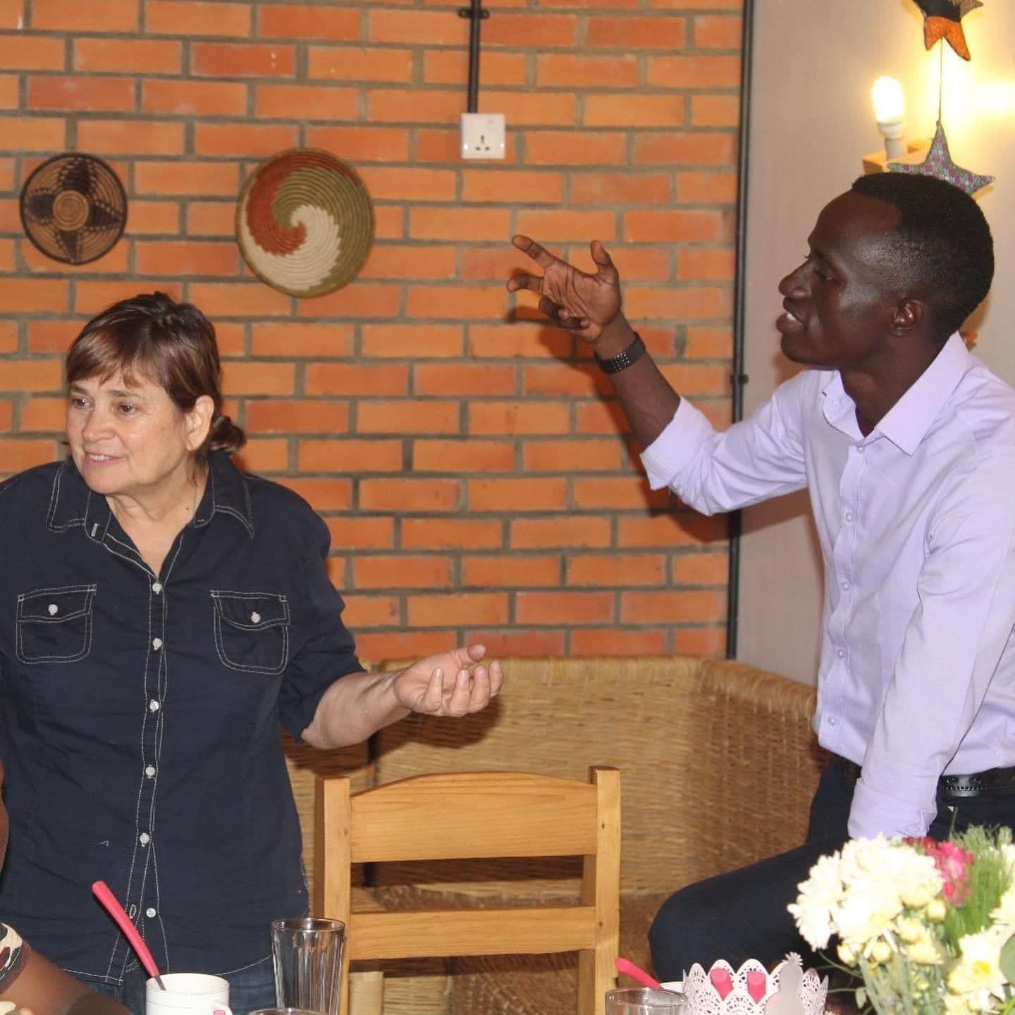 A visitor and Bertrand Ishimwe in conversation over dinner in Kigali