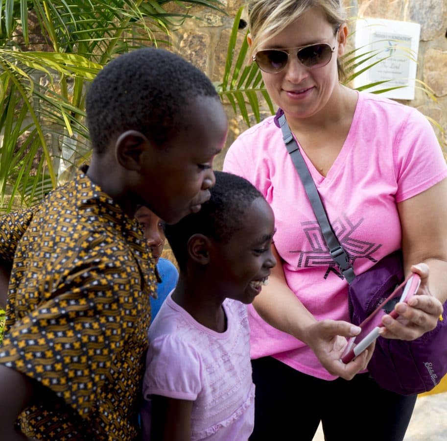 A visitor showing photos on her phone to two delighted children